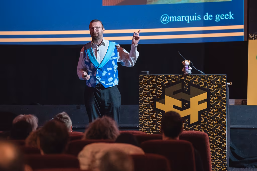 Steven stands on FFConf stage wearing a jaunty waistcoat and shirt, and placed on the podium is a tiny crocheted Ada Lovelace